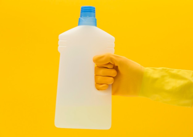 Hand in yellow rubber glove with cleaning product