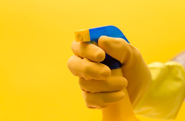 Hand in yellow rubber glove with cleaning product