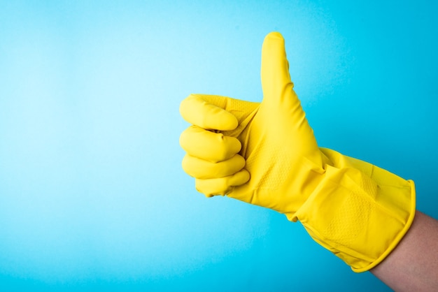 Hand in yellow rubber gloves on blue