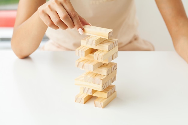 Hand of a young business woman to play wood block game with strategy and business systematic project management