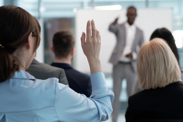 Hand of young female employee wishing to answer question of lecturer