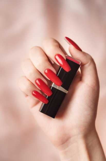 The hand of a young girl with a bright red manicure on her nails