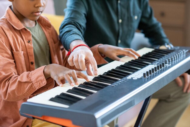 Hand of young teacher of music pointing at one of keys of piano keyboard