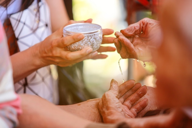 Hand of young woman pour water and flowers on the hands. 