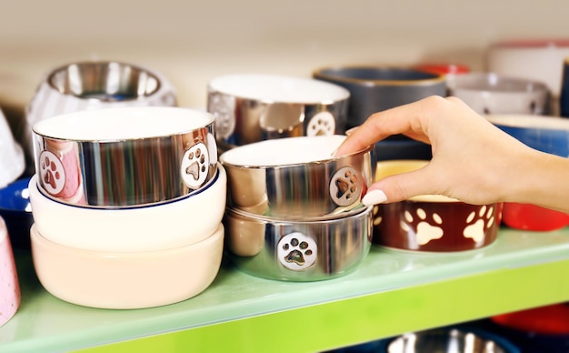 Hand of young woman selecting bowl in pet shop close up view