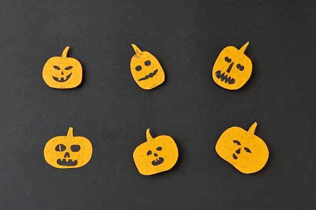 Handcraft decoratide pattern from flying smiling and laughing yellow pumpkins on a black background