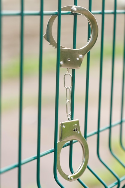 Handcuffs hang on a metal grille. High quality photo