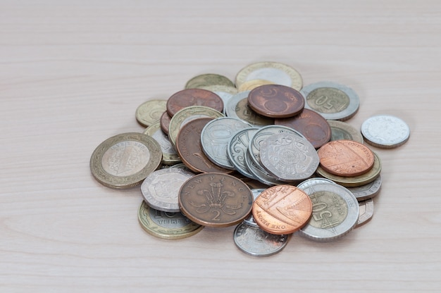 A handful of coins of different countries, color, dignity and size are scattered on the table.