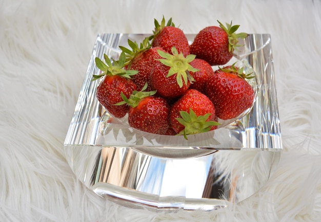 A handful of delicious strawberries on a decorative glass plate Light fur background