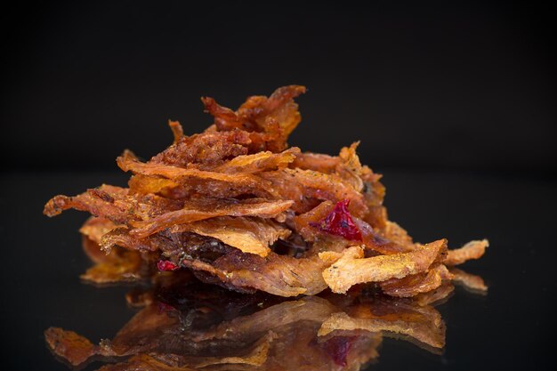 handful of dried meat marinated with spices isolated on a black background Beer snack