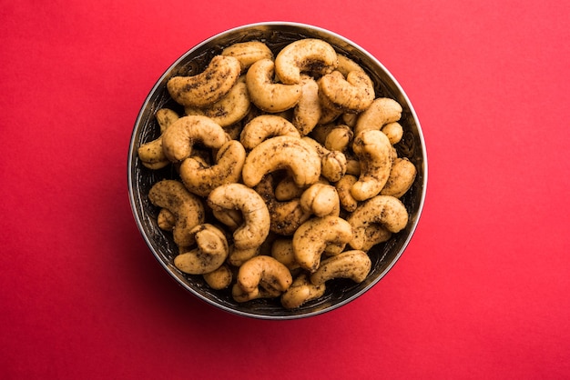 A handful roasted spiced cashew nuts  or masala kaju served in a bowl, selective focus