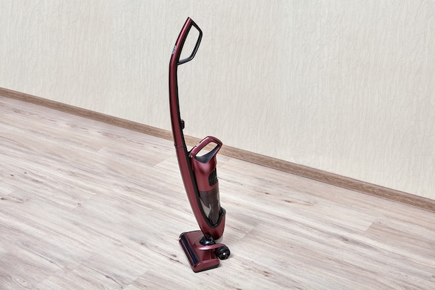 Handheld vacuum cleaner with separate small dust tank in an empty room.