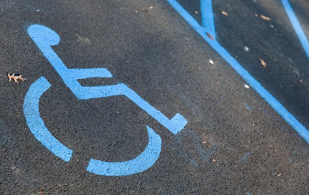 Photo handicap parking sign in blue and white on a paved lot symbolizing accessibility and inclusivity in