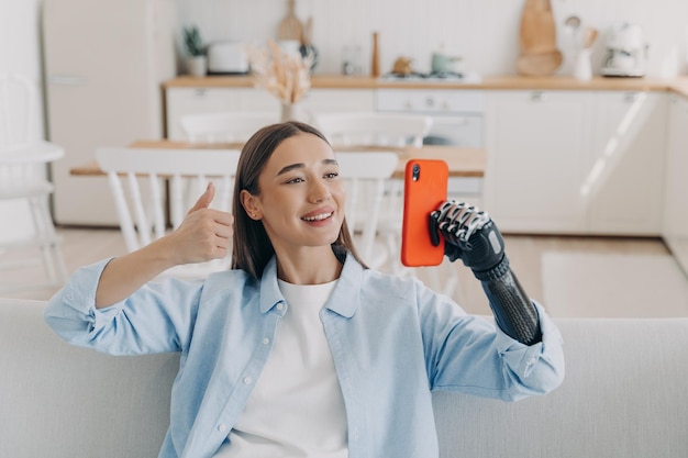 Handicapped confident woman has video call on smartphone Girl is holding phone with artificial arm