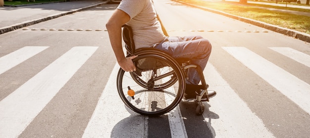 Handicapped man in wheelchair crossing street road.