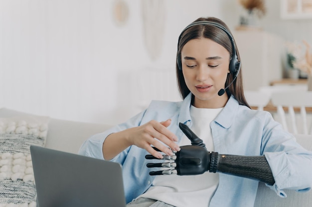 Handicapped young woman with artificial arm in headset at home Freelancer has online meeting