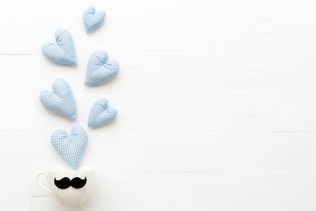 Handmade blue heart splash out from coffee cup on white table background.