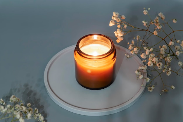 Handmade burning candle from paraffin and soy wax in glass jar on concrete tray Aroma Candle making Luxurious decoration home interior decor with burning aroma candle with white dry flower