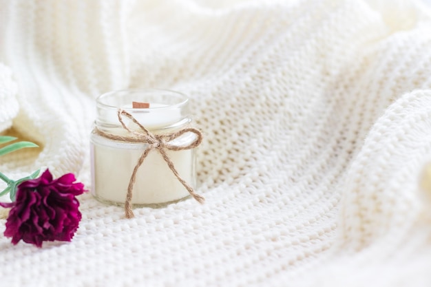 Handmade candle with red flower on white cozy blanket