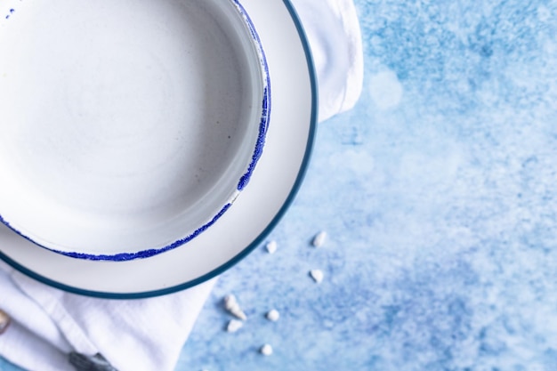 Handmade ceramic white plates with blue stripe on the edge and empty seashells