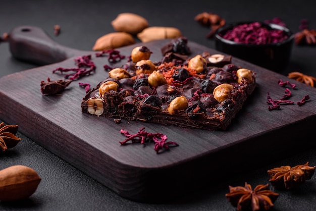 Handmade chocolate with berries nuts and spices on a dark background