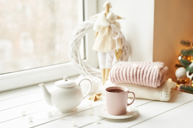 Handmade doll with tea set and marshmallows near window. Cozy winter morning breakfast. Christmas concept and mood. 