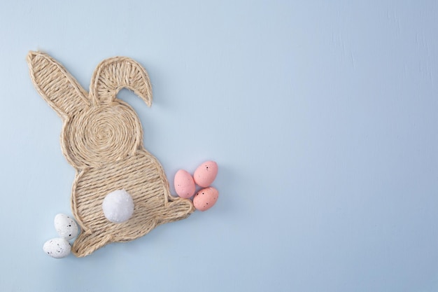 Handmade easter bunny made of strings with eggs on a light background top view