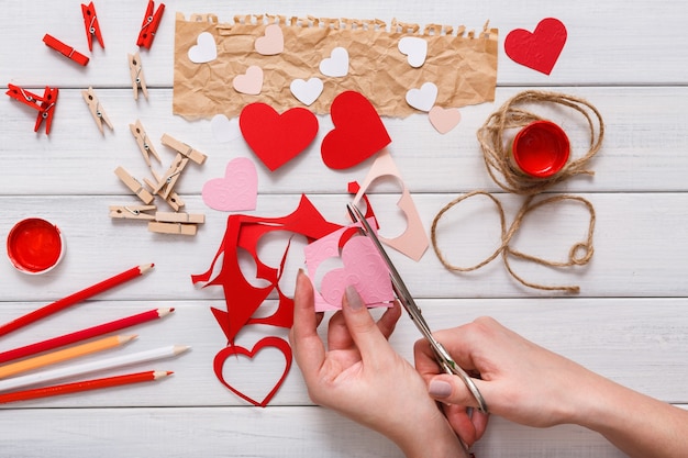 Handmade gift greeting heart creating, cut and paste , craft paper and diy tools on white wood