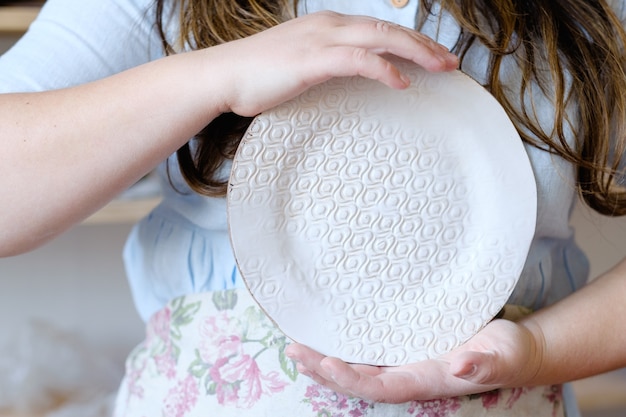 Handmade hobby pottery courses. master class at workshop. potter holding craft clay crockery plate