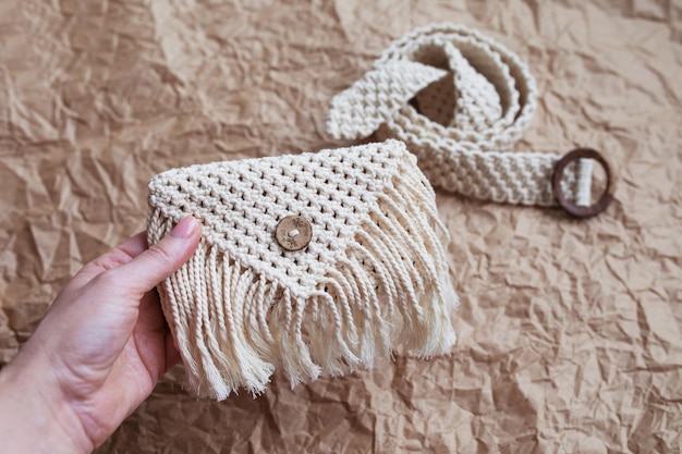 Handmade macrame belt bag on craft paper background ECO friendly natural macrame cotton waist bag Hobby knitting handmade macrame Modern summer concept