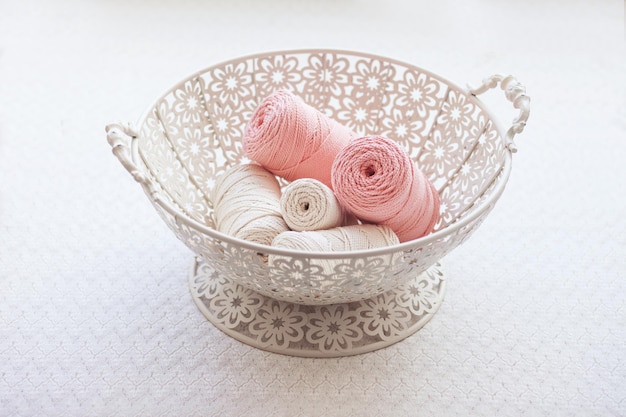 Handmade macrame braiding and cotton threads in basket on white background Cotton macrame cords