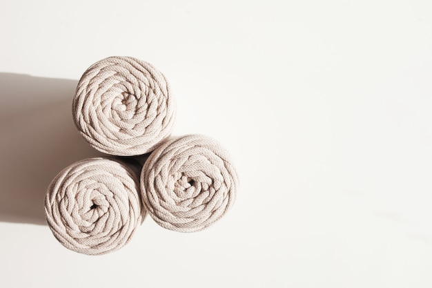 handmade macrame braiding and natural cotton threads stack on a white background with shadows