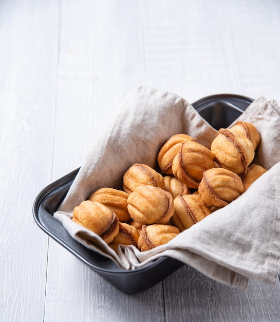 Handmade nuts baked with caramel in a baking dish on a white table. Copy space