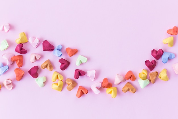 Handmade paper heart on pink background in top view