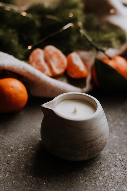 Handmade scented candle on a gray concrete background next to tangerines Gifts for Christmas New Year39s comfort at home