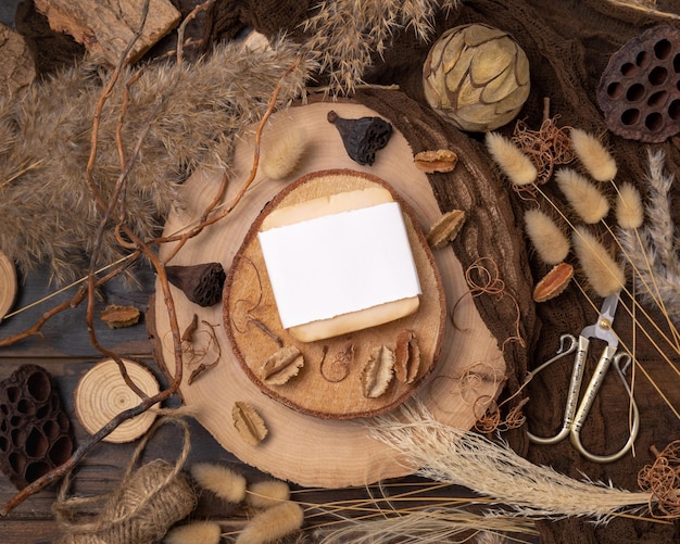 Handmade soap bar with blank label on wood near natural decorations top view Mockup