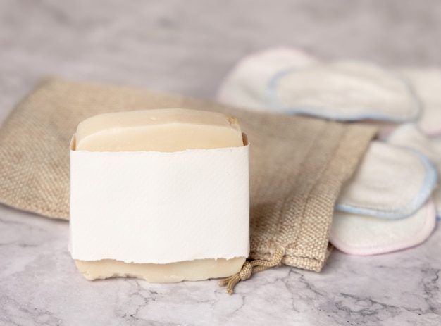 Handmade soap mockup and reusable make-up remover pads with a bag on a white marble close up