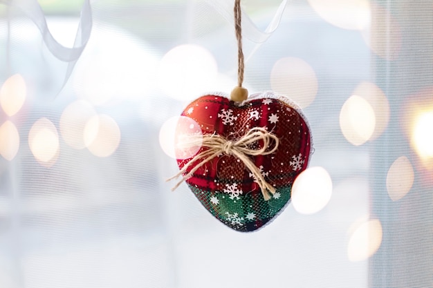 handmade soft Christmas tree toy made of fabric of red and green color with a bow of string hangs