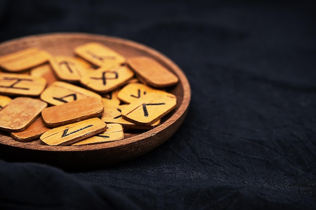 Handmade wooden runes on black fabric Heap of Scandinavian runes for divination close up