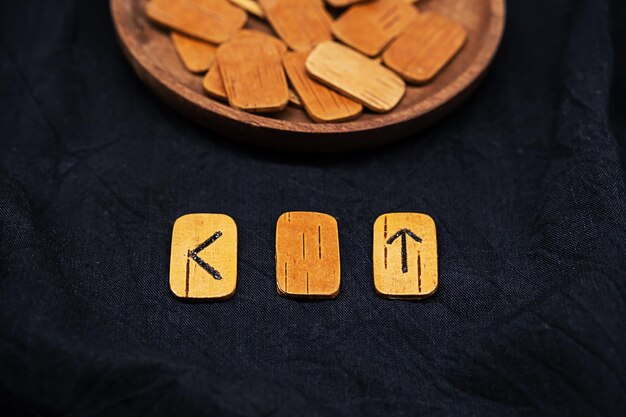 Handmade wooden runes on black fabric Heap of Scandinavian runes for divination close up