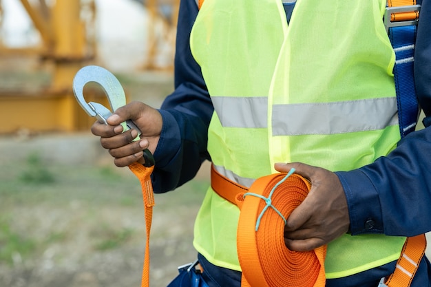 Hands of African builder preparing safety equipment before work