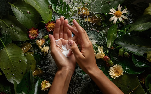 Hands apply cream against a backdrop of natural elements like leaves flowers and water highlight