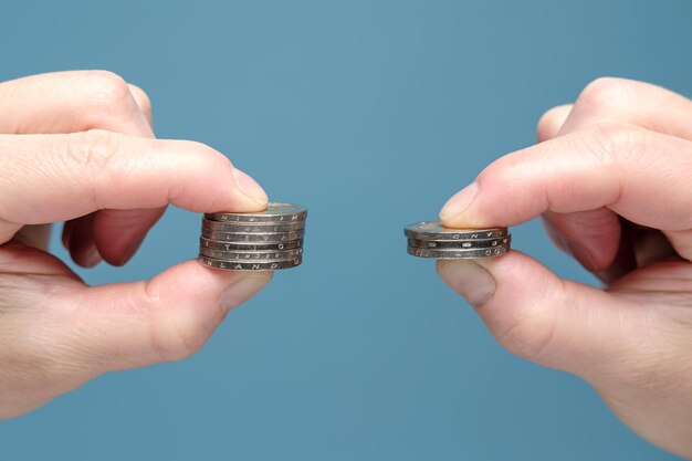 Hands are comparing two stacks of coins of different sizes indicating worsening financial situation