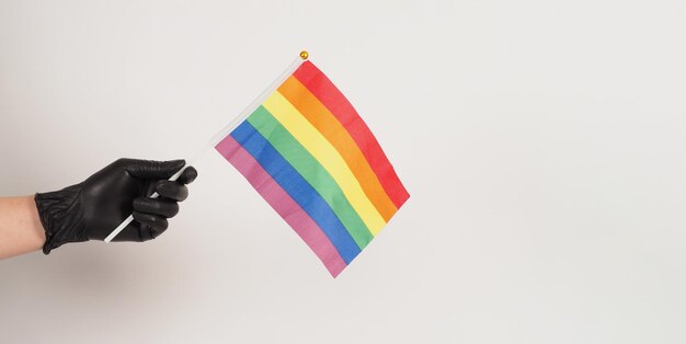 Hands are holding a rainbow flag Hands are wearing black latex gloves