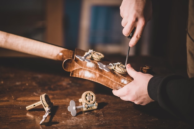 Hands of artisan luthier screwing, building a double bass