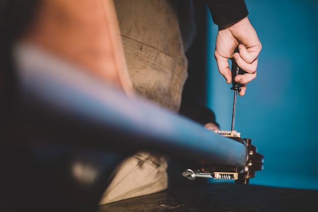 Hands of artisan luthier varnishing, building a double bass