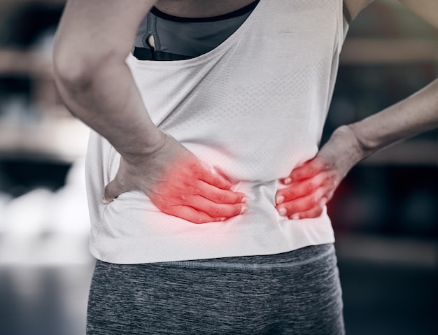 Hands back pain and overlay with a sports woman holding her muscle while suffering from cramp or injury Fitness exercise and red highlight with a female athlete struggling with an injured spine