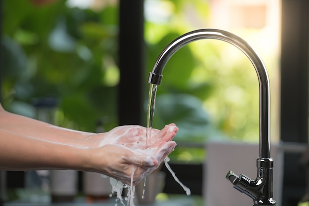 Hands being washed scrubbed and rinsed using disinfectant soap for hygiene and protection against COVID-19 and other dieseases