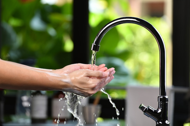 Hands being washed scrubbed and rinsed using disinfectant soap for hygiene and protection.