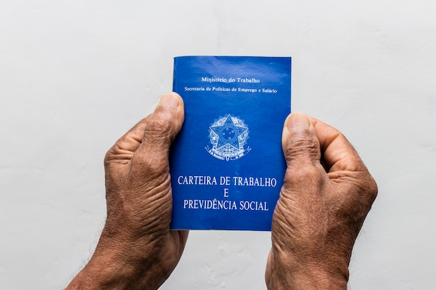 Hands of black senior man holding work book, Brazilian social security document